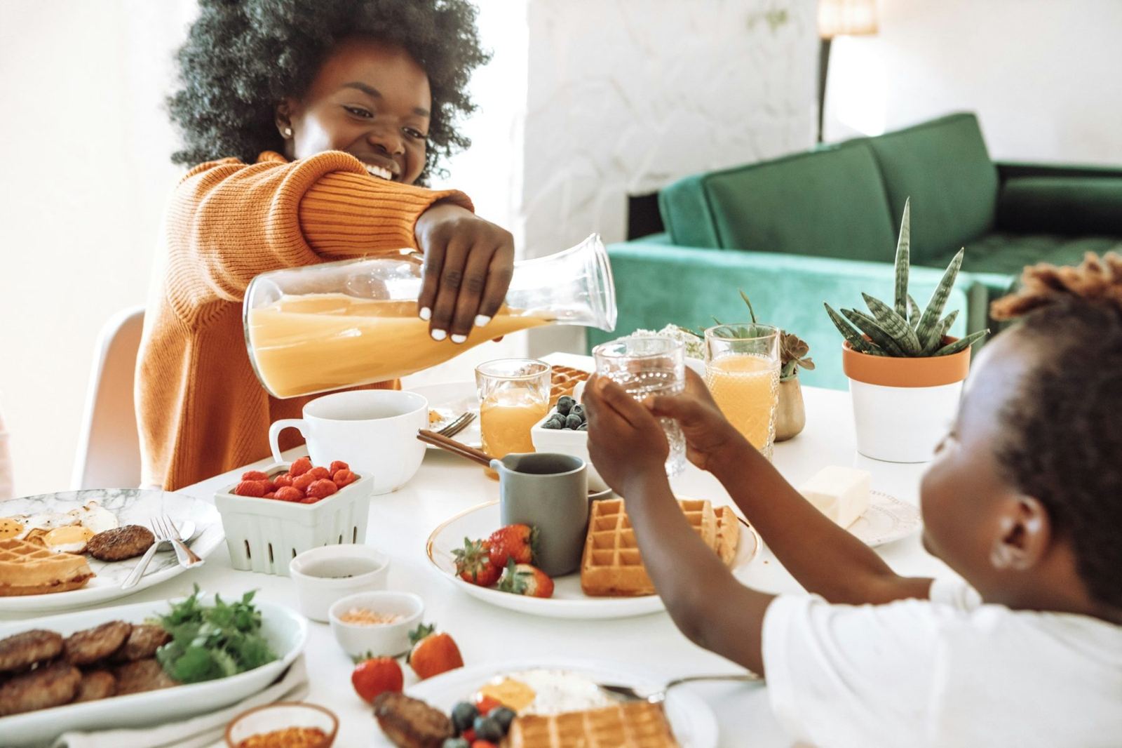 Adult serving fresh juice at a shared breakfast table